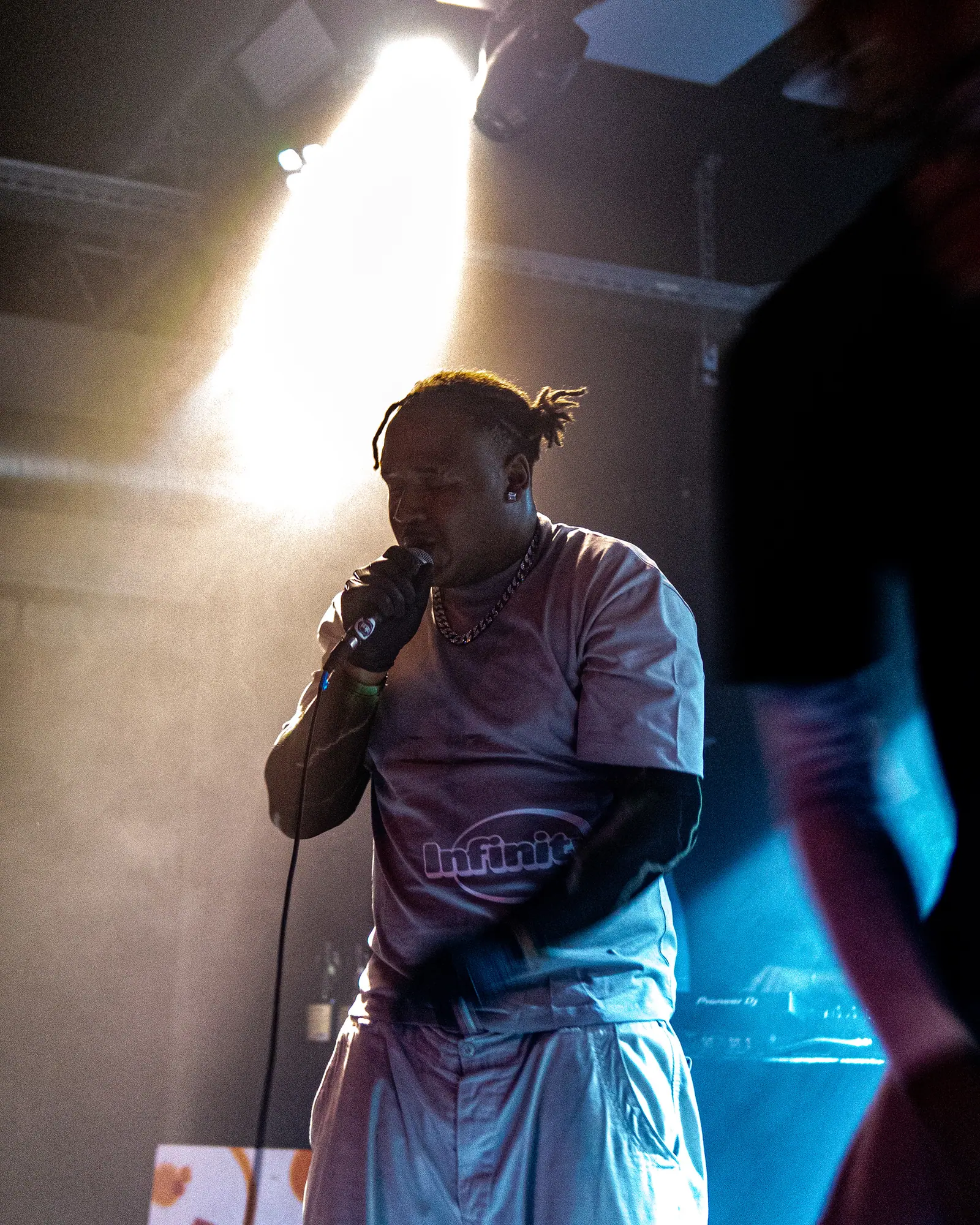 A performer sings with eyes closed in a beam of warm stage light.